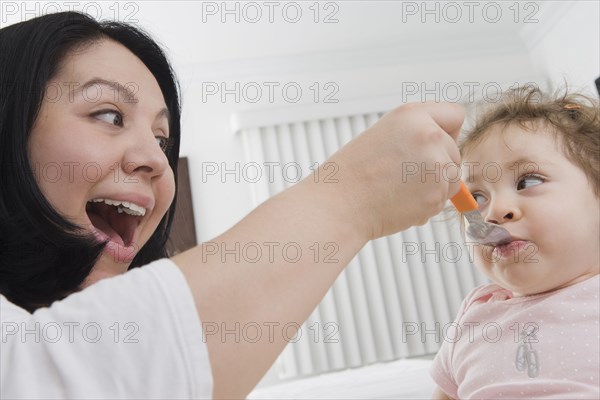 Hispanic mother feeding baby girl