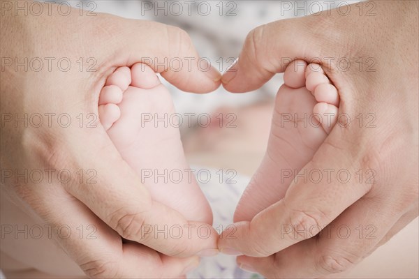 Close up of Hispanic mother cupping baby boy's feet