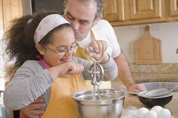 Hispanic father and daughter baking in kitchen