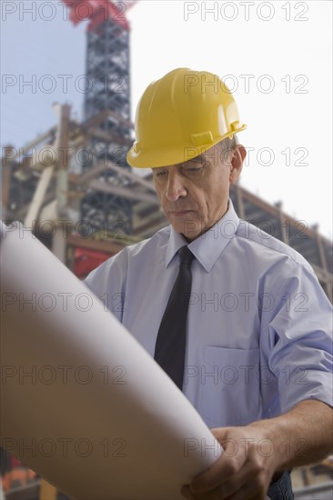 Hispanic architect reviewing blueprints at construction site
