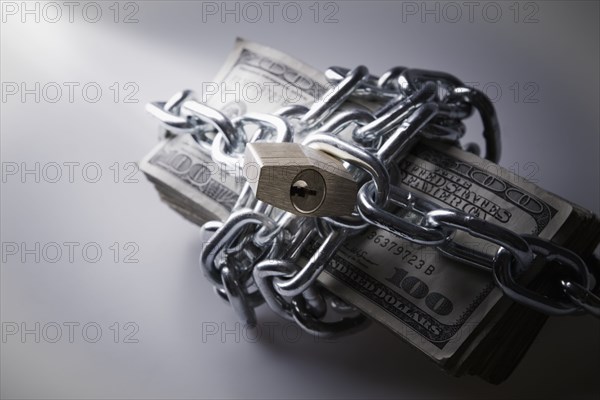 Chains and padlock around stack of dollar bills