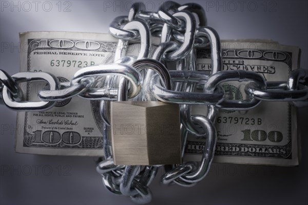Chains and padlock around stack of dollar bills