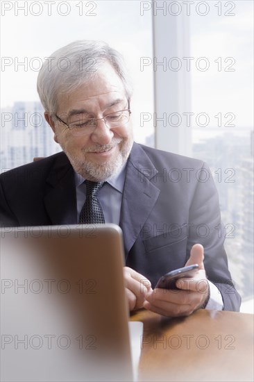 Hispanic businessman using cell phone at desk