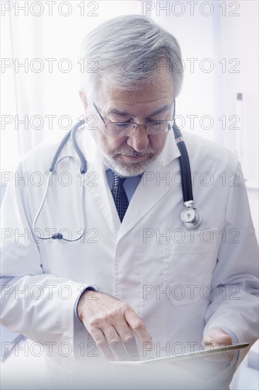 Hispanic doctor reading medical chart in hospital