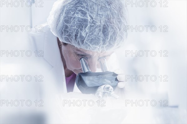 Hispanic scientist using microscope in lab