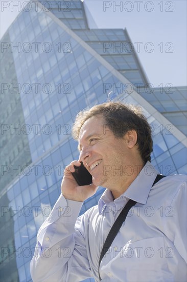 Hispanic businessman talking on cell phone on city street