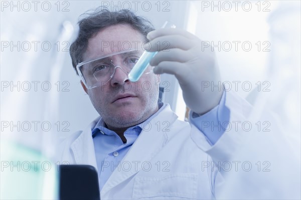 Hispanic scientist examining test tube in lab