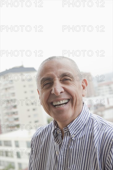 Hispanic senior man smiling near scenic view of cityscape