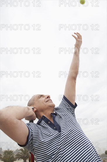 Hispanic senior man playing tennis outdoors