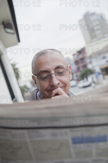 Hispanic senior man reading newspaper