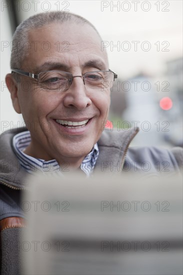 Hispanic senior man reading newspaper