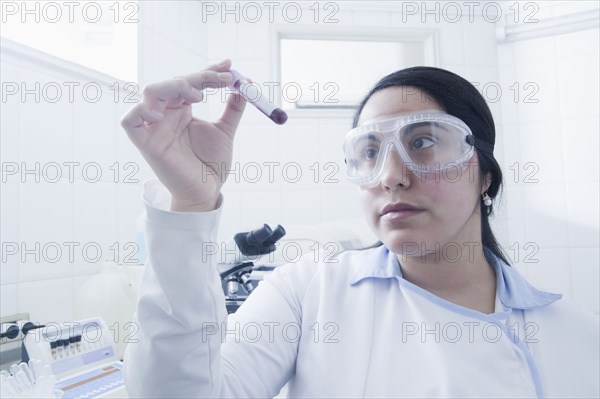 Hispanic scientist examining blood sample in laboratory