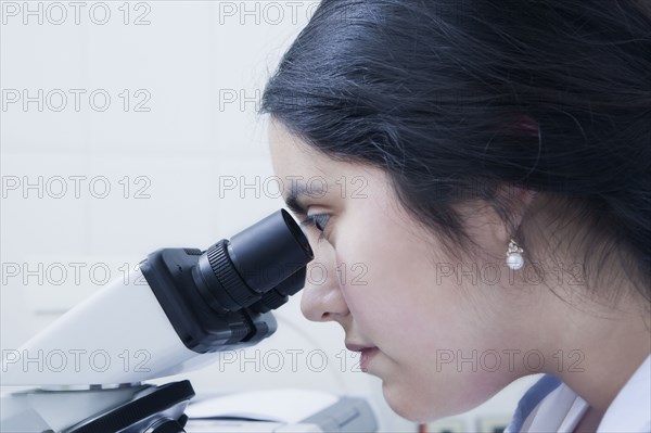 Hispanic scientist using microscope in laboratory