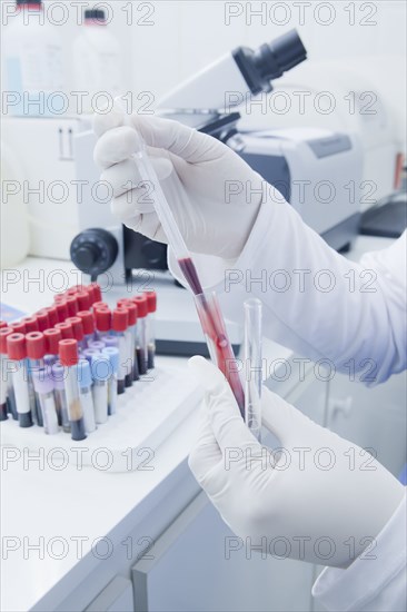 Hispanic scientist pipetting blood sample in laboratory