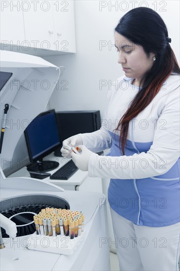 Hispanic scientist testing blood sample in laboratory centrifuge