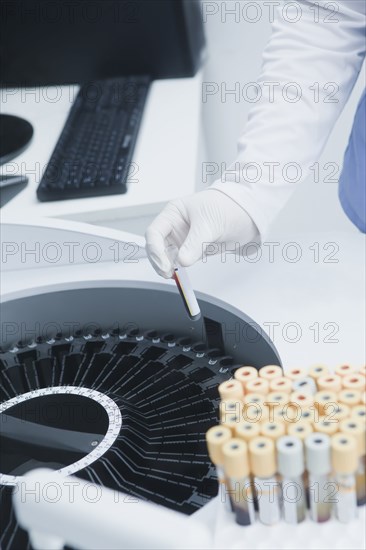 Hispanic scientist testing blood sample in laboratory centrifuge