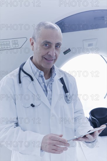 Hispanic doctor using digital tablet near MRI scanner
