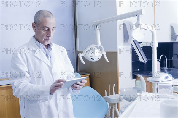 Hispanic dentist using digital tablet in office