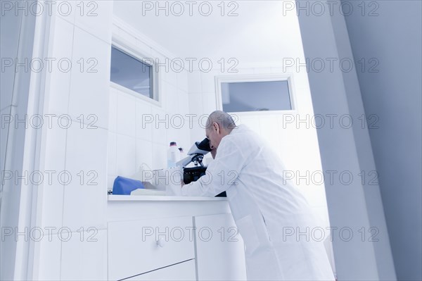 Hispanic scientist using microscope in lab