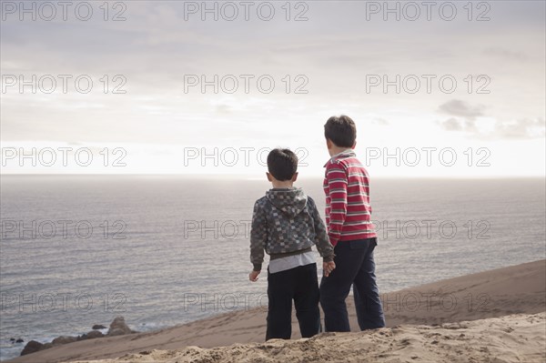 Hispanic brothers standing on sand dunes on beach