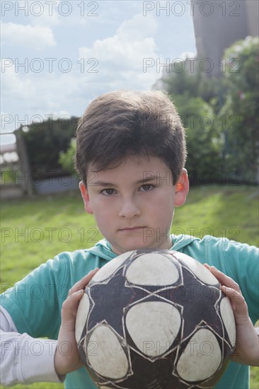 Hispanic boy holding soccer ball in backyard