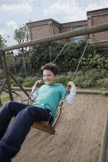 Hispanic boy playing on swing in backyard