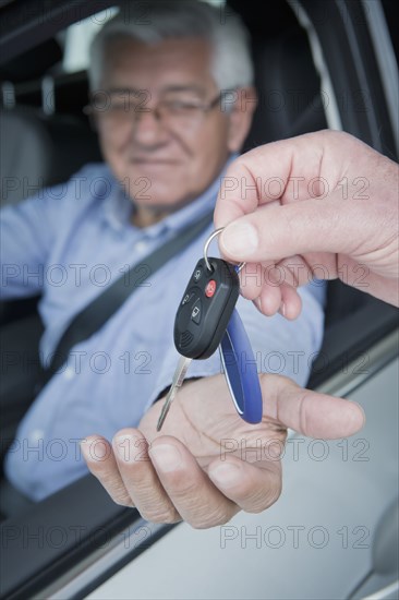 Hispanic car salesman handing keys to customer