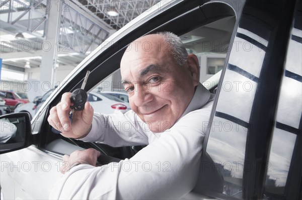 Hispanic man holding keys to new car