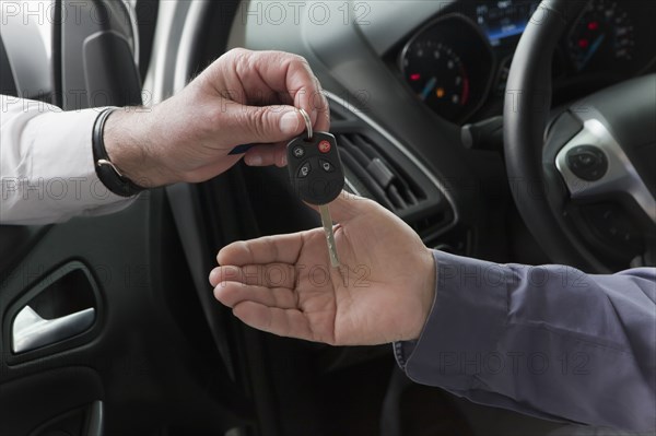 Hispanic car salesman handing keys to customer