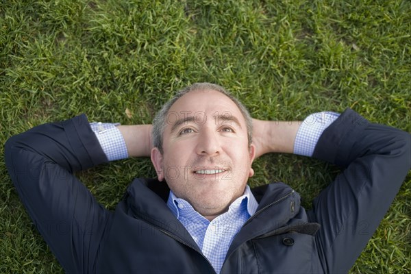 Hispanic businessman laying on grass