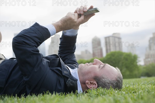 Hispanic businessman using cell phone in urban park