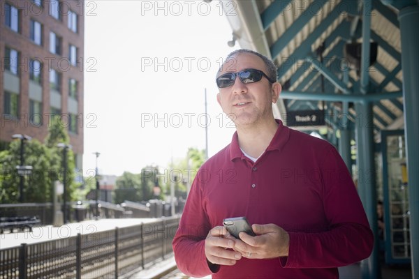Hispanic man holding cell phone at train station