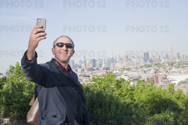 Hispanic man taking selfie with New York cityscape