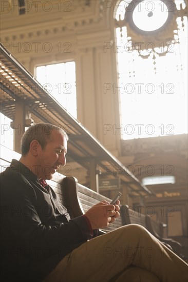 Hispanic man reading newspaper in train station
