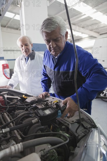 Older Hispanic mechanics repairing car in garage