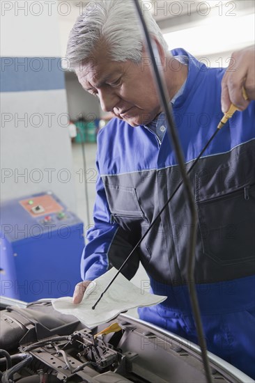 Older Hispanic mechanic repairing car in garage