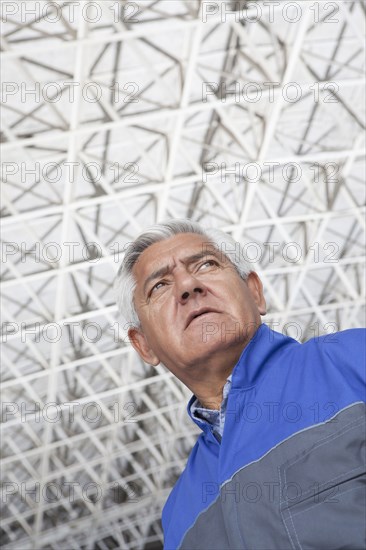 Low angle view of older Hispanic mechanic in warehouse