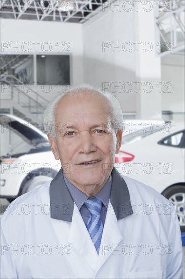 Older Hispanic mechanic standing in garage