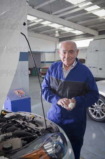 Older Hispanic mechanic working on car in garage
