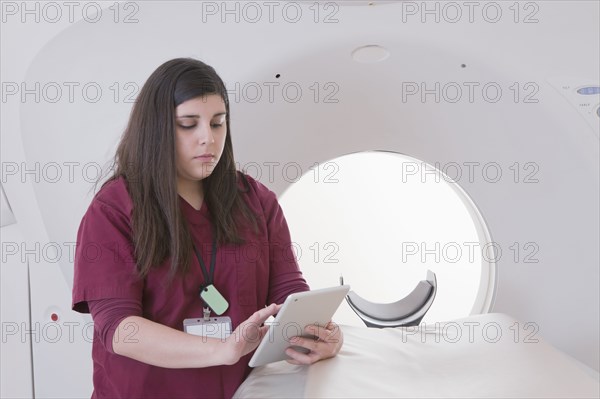 Hispanic nurse using digital tablet in MRI room