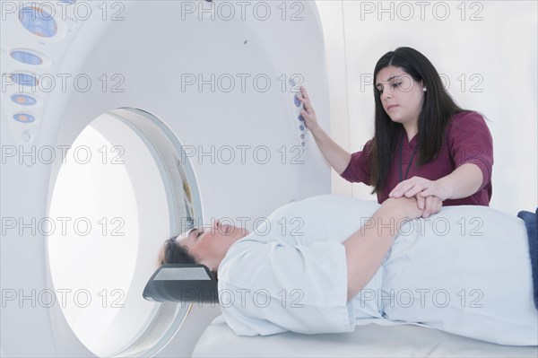 Hispanic nurse comforting patient in MRI machine