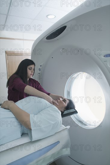 Hispanic nurse examining patient in MRI machine