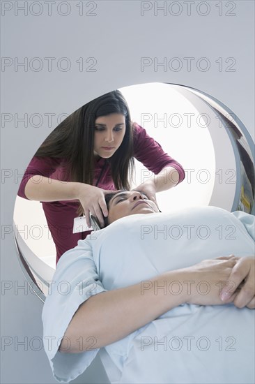 Hispanic nurse examining patient in MRI machine