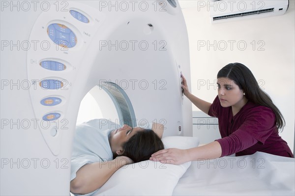 Hispanic nurse examining patient in MRI machine