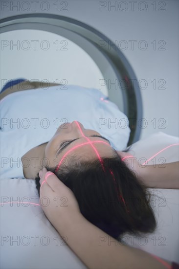 Hispanic nurse examining patient in MRI machine