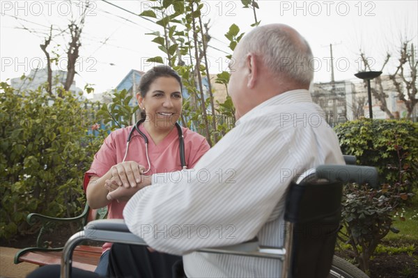 Hispanic nurse comforting patient in wheelchair