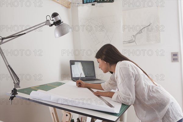 Hispanic architect drawing at drafting table