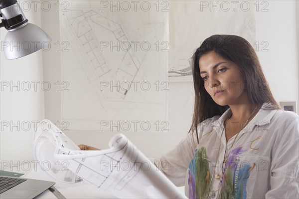 Hispanic architect reading blueprints