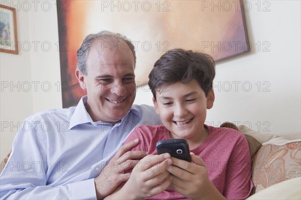Hispanic father and son texting on cell phone
