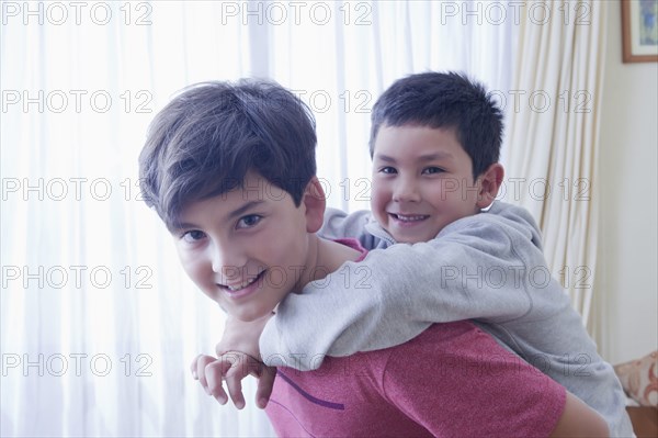 Hispanic boy carrying brother piggyback